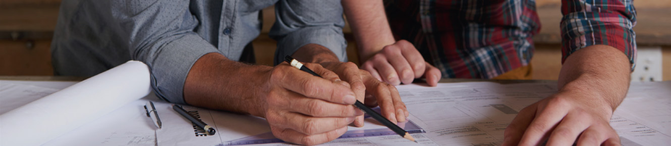 photo of two men drawing out work plans with a pencil  